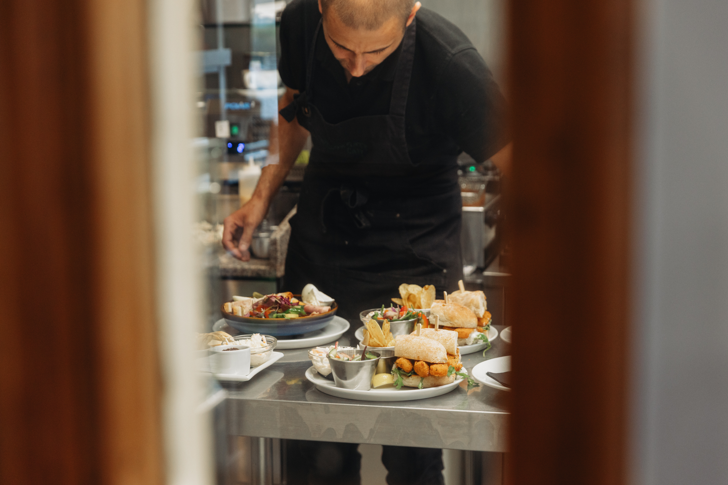 Chef plating freshly prepared sandwiches and sharing plates in the kitchen at Willowgate Café near Perth