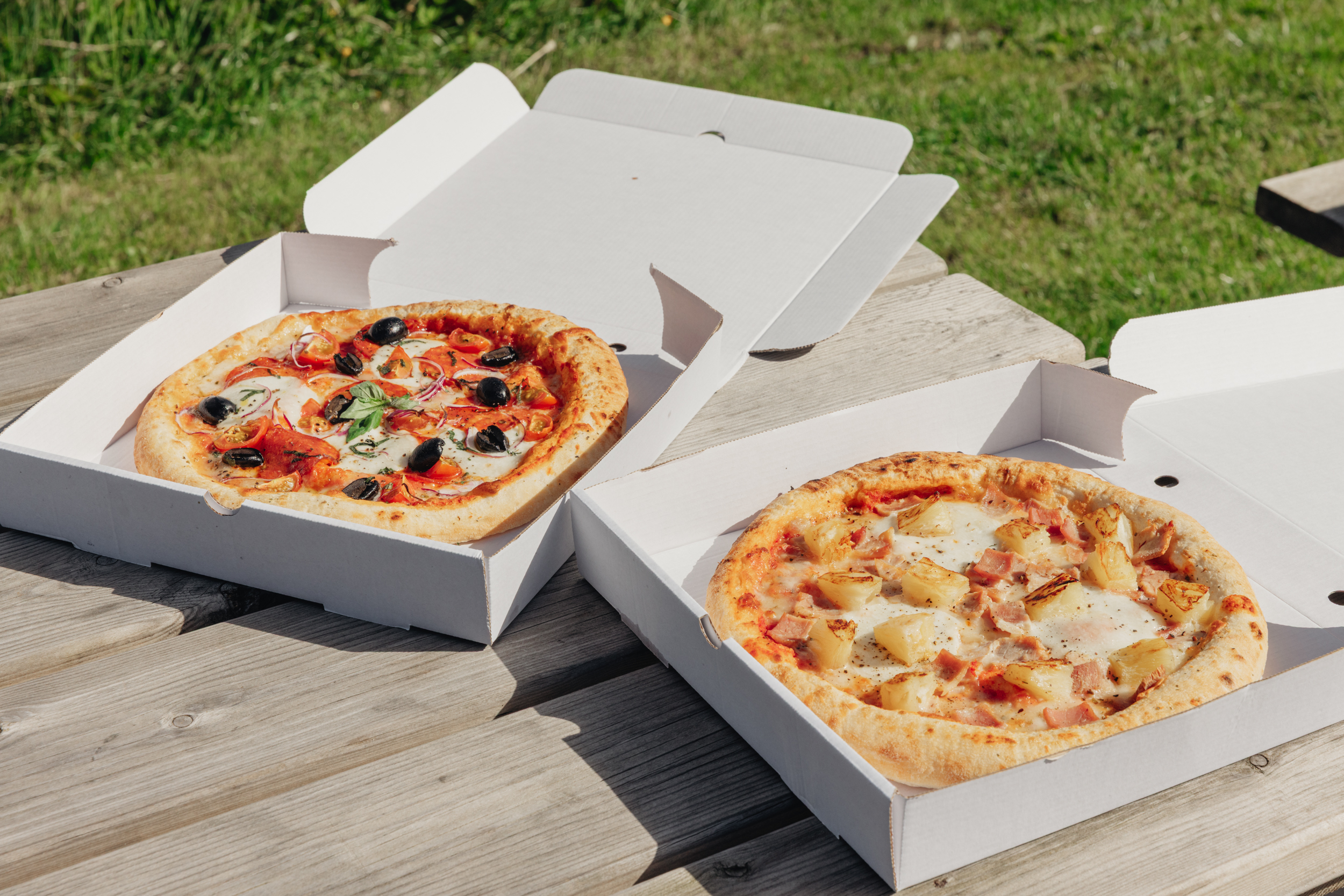 Two wood-fired pizzas served in takeaway boxes on an outdoor picnic table at Willowgate Café near Perth
